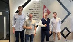 Quatro homens posam sorridentes em um escritório, incluindo o economista Paulo Guedes, diante de uma parede com uma citação sobre liberdade econômica atribuída ao Barão de Mauá.